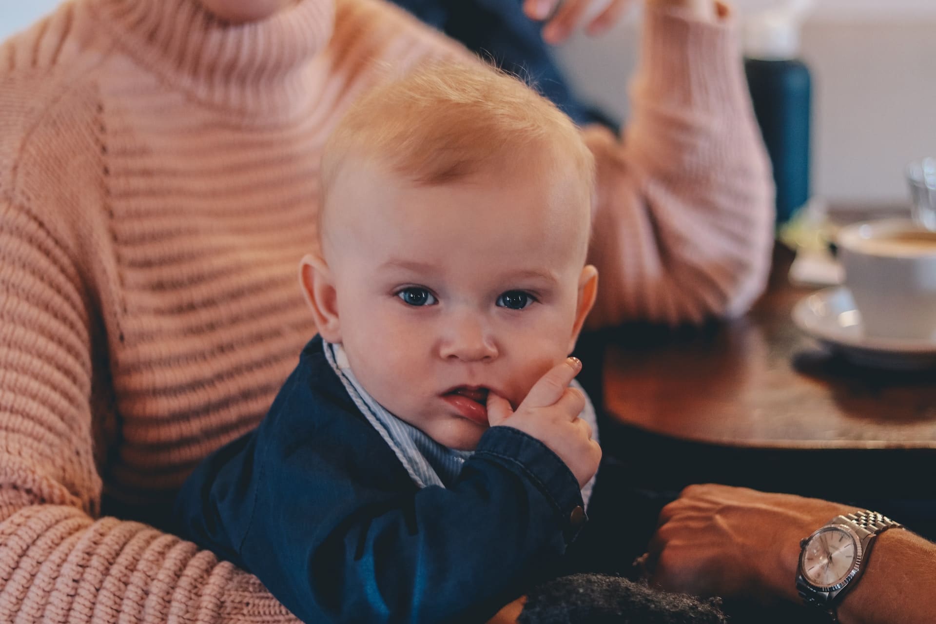 A parent gently discouraging their child from thumb-sucking, offering a toy as an alternative.