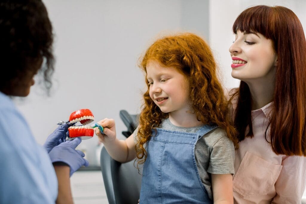 A pediatric dentist using calming techniques to ease a young patient's dental anxiety during a check-up.