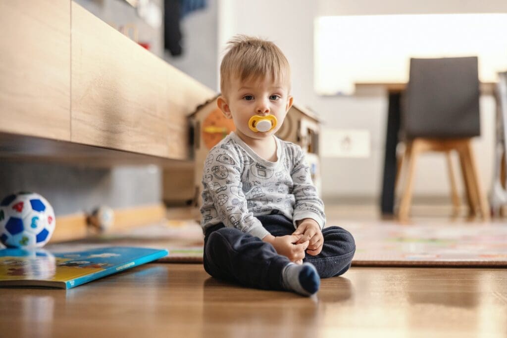 A child holding a pacifier while a concerned parent discusses dental concerns with a dentist.