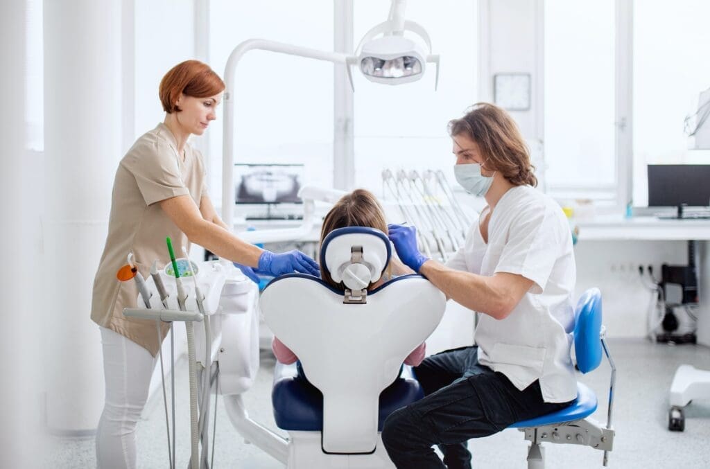 A child feeling relaxed and smiling at the dental office, thanks to supportive techniques used by the best pediatric dentist in Newton, MA.