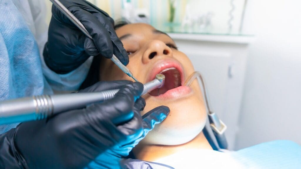 A close-up photo of a child smiling, showing dental sealants on their back teeth and wearing a sports mouthguard.