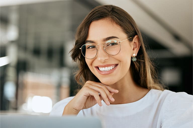 Young woman with glasses smiling with dental implants in Newton