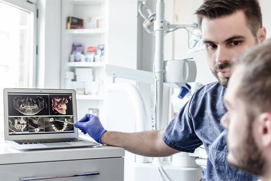 A dentist showing a patient their diagnostic scans