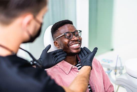 A smiling man getting his teeth cleaned at the dental office