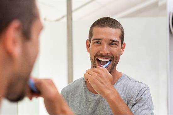 Patient in Newton brushing their teeth after getting dental implants