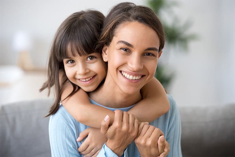 A child hugging their parent from behind.