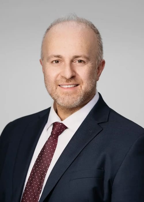 Profile image of Dr. Konstantinos Vazouras smiling in a suit and tie.