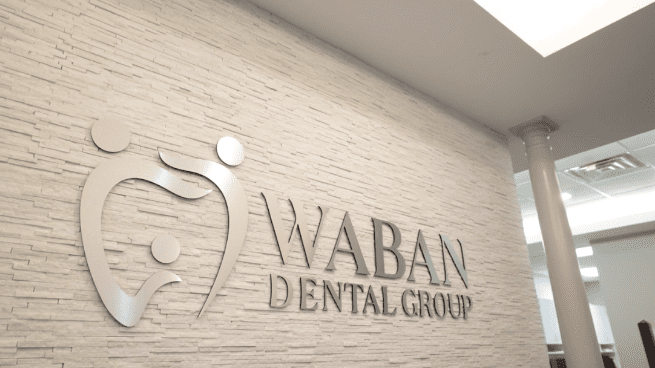 Waban Dental Group logo displayed on the office wall, representing their dental services and brand identity.
