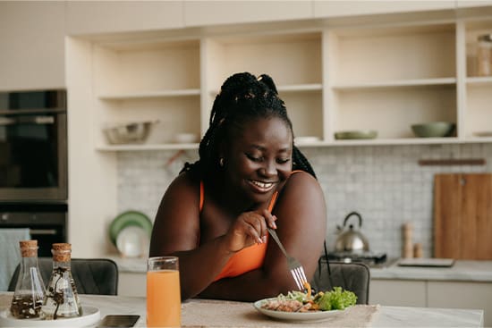 Woman smiling while eating lunch in kitchen.