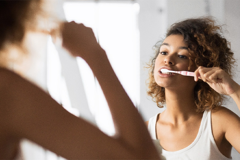 Newton patient checking teeth in mirror.