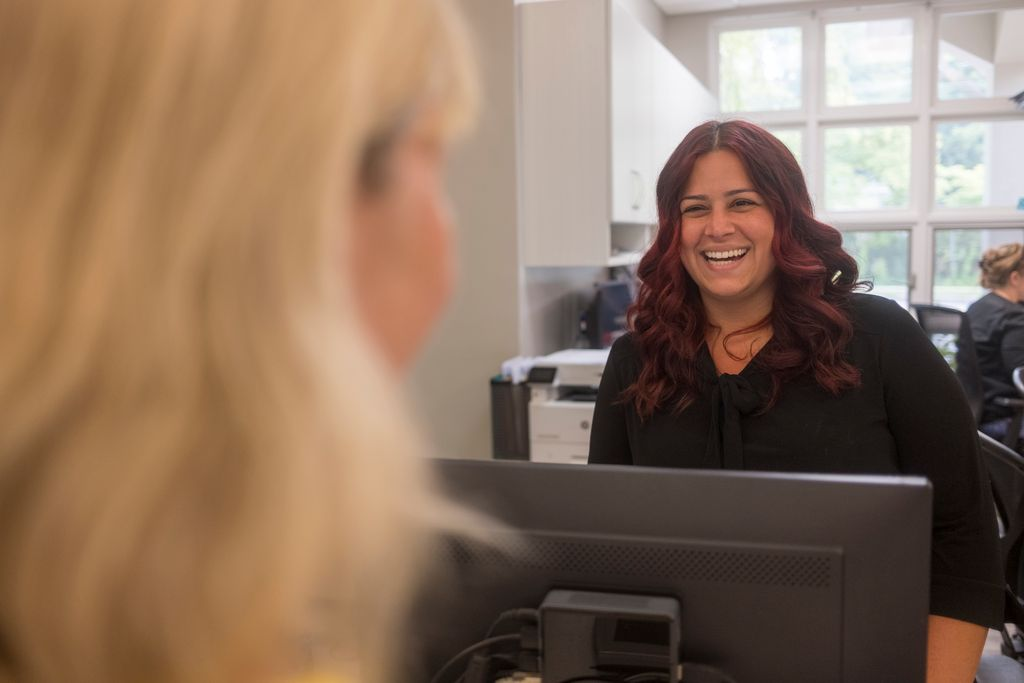 Patient and front desk operator smiling in Newton.