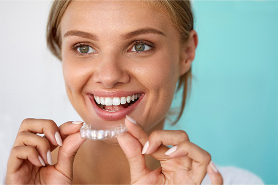 Patient smiling while holding teeth whitening tray.
