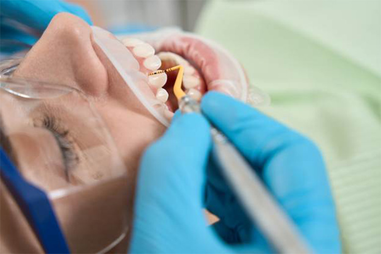 Dentist performing gum disease treatment on patient.