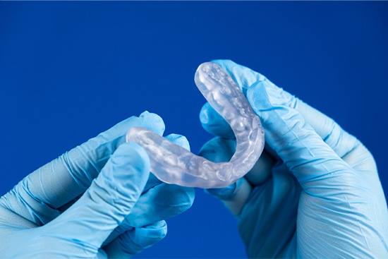 Gloved hands holding an occlusal splint.