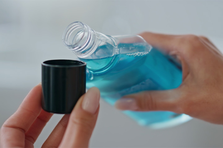A person pouring a capful of mouthrinse.