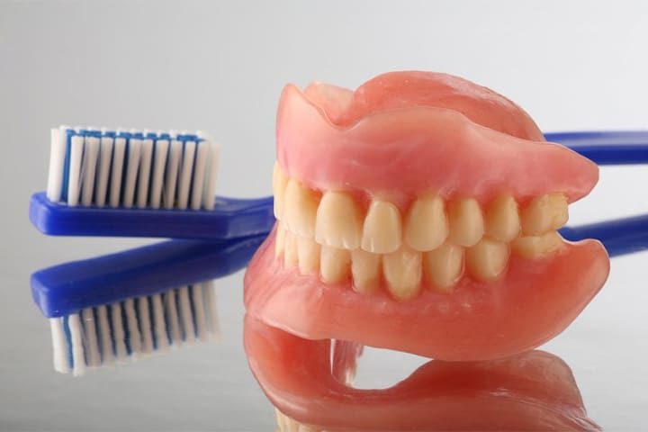 Full set of dentures and a toothbrush.
